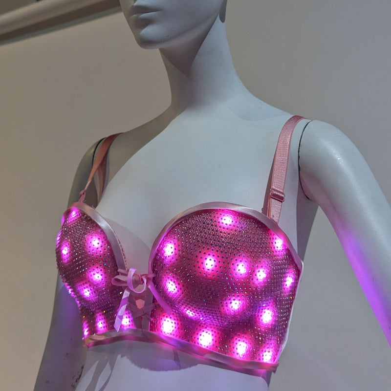 Neon Cowboys LED rhinestone push up bra glowing pink on a mannequin with sparkling studded sequin cups, light up bra rave outfit stagewear for go-go dancers, burlesque performers and showgirls, perfect for festival outfits, rave parties and EDM concerts, Neon Cowboys