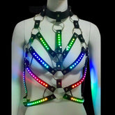 LED Rib Cage Harness glowing in rainbow colors — a color-changing light-up cage body harness with black patent straps and silver O-rings, for raves, festivals, goth and performers.