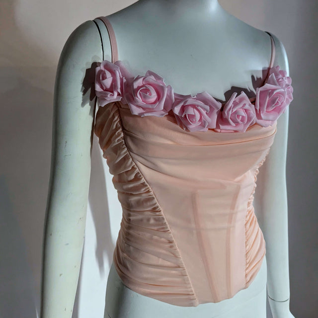 A blush ruched corset on a mannequin with soft pink foam roses along the neckline shown with lights off in daylight, a light up corset and LED rose corset stagewear for go-go dancers, burlesque performers and festival dancers at raves and music festivals, Neon Cowboys LED rose corset, Neon Cowboys