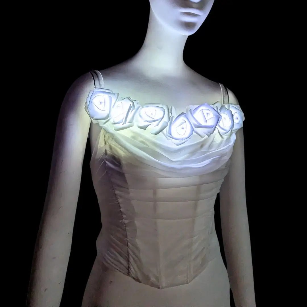 A white rose corset on a mannequin with LED light up roses glowing cool white, a light up corset and LED rose corset stagewear for go-go dancers, burlesque performers, brides and festival dancers at raves, weddings, and music festivals, Neon Cowboys LED rose corset, Neon Cowboys