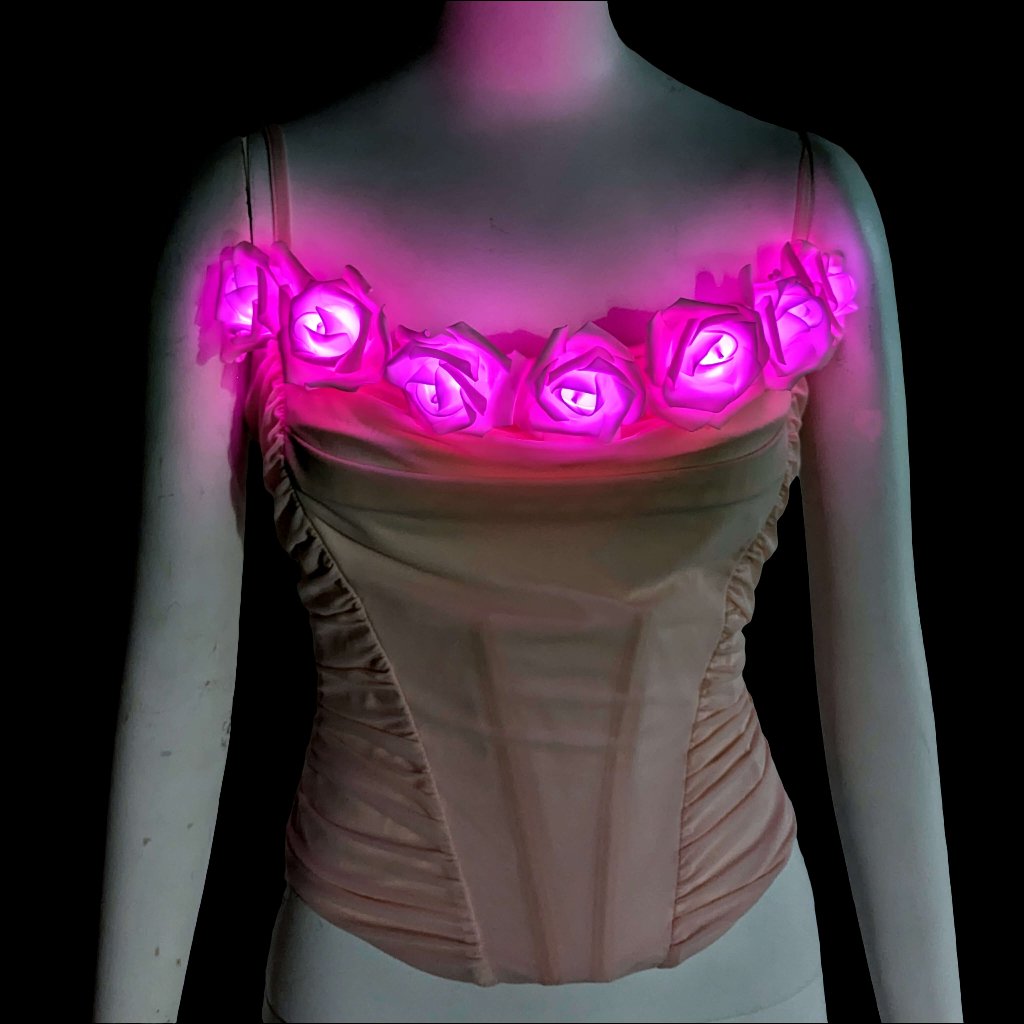 A blush ruched corset on a mannequin topped with LED light up roses glowing hot pink, a light up corset and LED rose corset stagewear for go-go dancers, burlesque performers and festival dancers, perfect for raves, music festivals, and Coachella, Neon Cowboys LED rose corset, Neon Cowboys