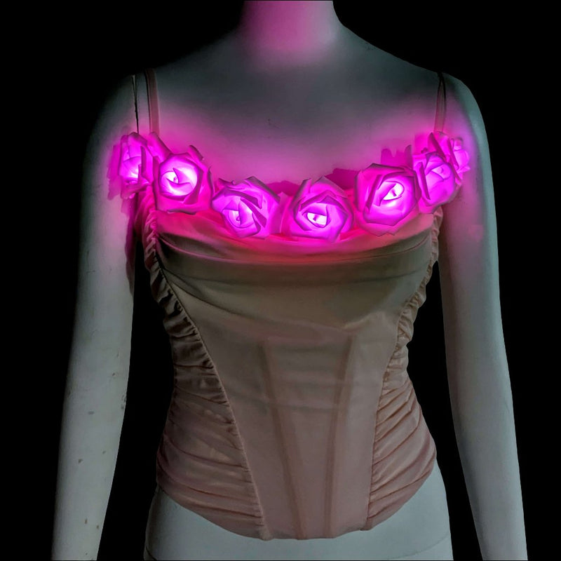A blush ruched corset on a mannequin topped with LED light up roses glowing hot pink, a light up corset and LED rose corset stagewear for go-go dancers, burlesque performers and festival dancers, perfect for raves, music festivals, and Coachella, Neon Cowboys LED rose corset, Neon Cowboys