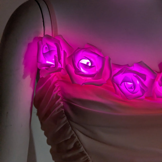 A close-up of the LED light up roses glowing pink along the neckline of the blush rose corset, a light up corset and LED rose corset stagewear for go-go dancers, burlesque performers and festival dancers at raves, music festivals, and Coachella, Neon Cowboys LED rose corset, Neon Cowboys