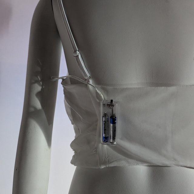 A side view of the white rose corset showing the clear removable AA battery pack that powers the LED roses, a light up corset and LED rose corset stagewear for go-go dancers, burlesque performers and festival dancers at raves, music festivals, and EDM concerts, Neon Cowboys LED rose corset, Neon Cowboys