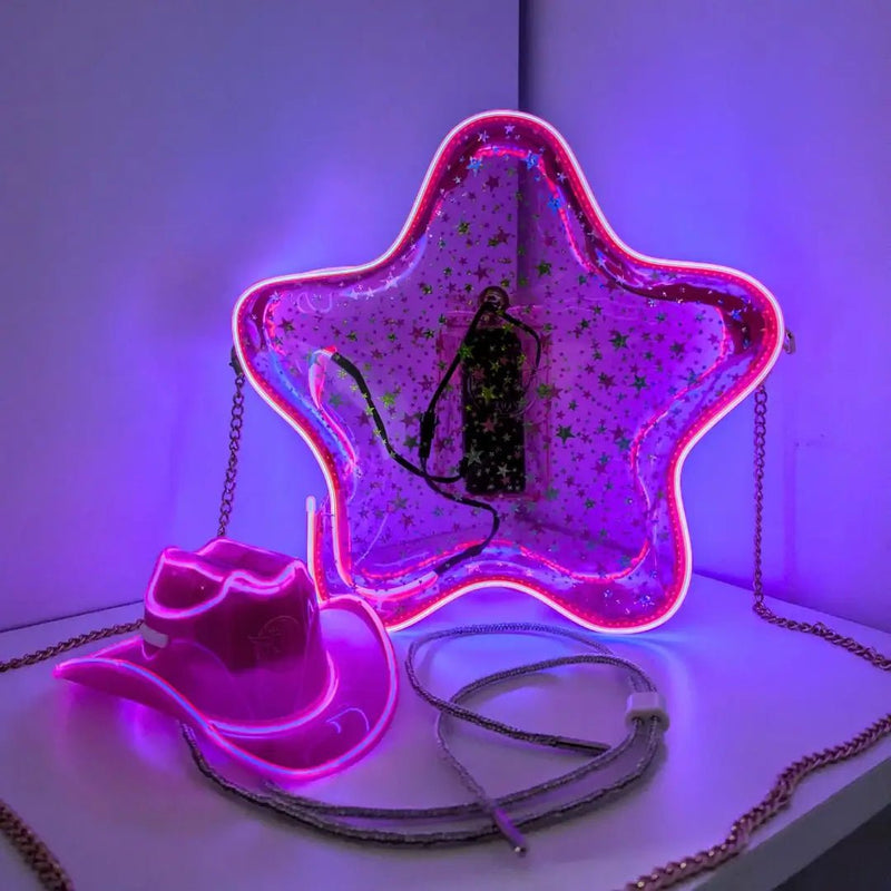 Pink LED Star Bag and Mini Neon Cowboy Hat Bundle Pack, the pink star purse glowing beside a light up mini neon cowboy hat in a purple lit corner, a clear bag policy purse and light up crossbody bag for concerts, a glowing fashion accessory perfect for space cowgirl Halloween costumes, bachelorettes, music festivals and birthday parties, Neon Cowboys