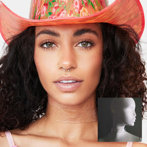 Woman with curly hair wearing pink cowboy hat and light up WANTED choker for country western themed bachelorette party outfit that combines festival fashion with fun glowing accessories