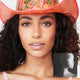 Woman with curly hair wearing pink cowboy hat and light up WANTED choker for country western themed bachelorette party outfit that combines festival fashion with fun glowing accessories