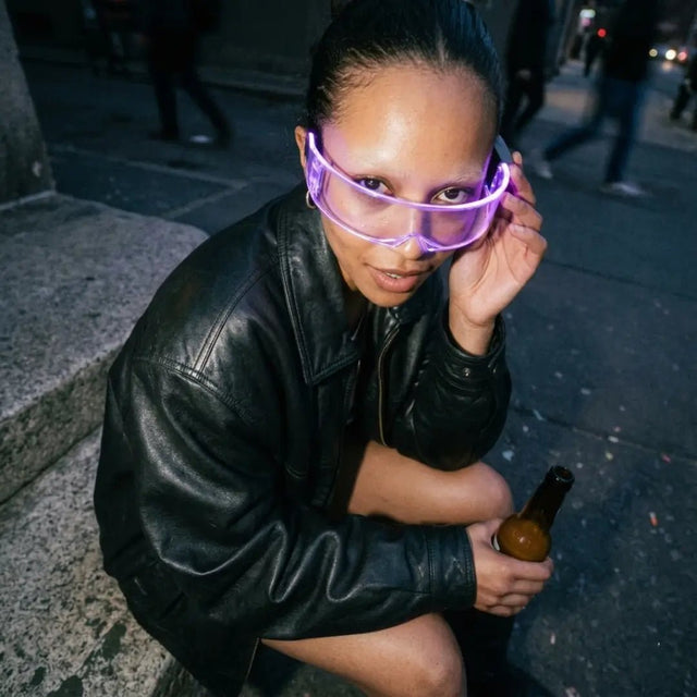 Woman in purple glowing LED cyber glasses and leather jacket on a city street at night, futuristic light up glasses and cyberpunk led glasses for raves, EDM concerts, nightlife, Pride, and Halloween costumes, Neon Cowboys