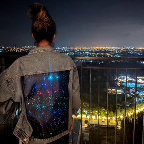 Light Up Denim Jacket Overlooking the City Night Sky - Woman Wearing Galaxy LED Jacket with City Skyline View - Night Out Fashion Statement for Concerts Music Festivals Bar Hopping Bachelorette Party Girls Night Out - Gamer Nerd Fashion Technology Outfit