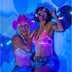 Two women in coordinating pink and blue light up fringe bralettes with cowboy hats showing matching festival outfits for country concerts and rodeo events