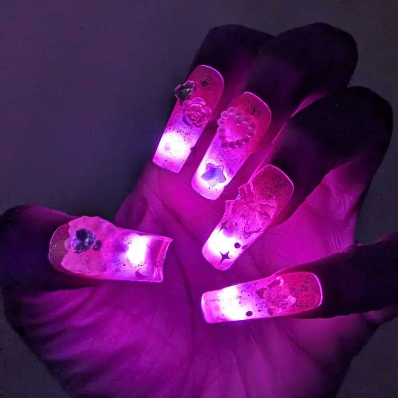 Close-up of pink glowing LED light-up press-on nails with hearts and roses held in a palm, wireless light up nail extensions and led press on nails accessories, perfect for a rave, music festival or bachelorette, Neon Cowboys