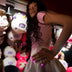 Model with pink glowing LED light-up press-on nails leaning near a claw-machine prize wall, wireless led press on nails and light up nails that glow for a rave, bachelorette or EDM concert, Neon Cowboys