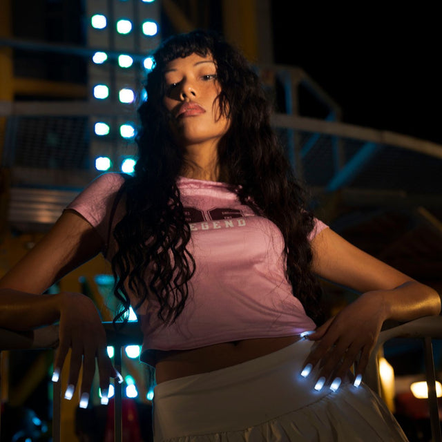 Woman at a night fair with white glowing LED light-up press-on nails resting on a railing, wireless led nails and light up nails that glow for a rave, wedding or music festival, Neon Cowboys