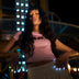 Woman at a night fair with white glowing LED light-up press-on nails resting on a railing, wireless led nails and light up nails that glow for a rave, wedding or music festival, Neon Cowboys