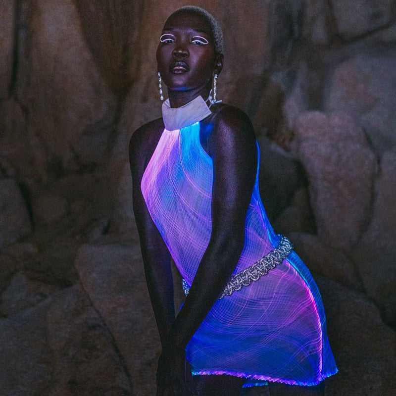 Model glows in a Neon Cowboys light up net dress with fiber optic mesh shining purple and blue at night, led festival stagewear for go-go dancers, burlesque performers and showgirls, perfect for raves, EDM concerts and music festivals, Neon Cowboys