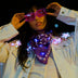 Woman lifting pink glowing LED party sunglasses over a light up star jacket and bandana at night, glowing festival sunglasses and cyberpunk led glasses for raves, EDM concerts, and Pride, Neon Cowboys