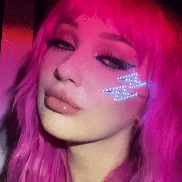 Close-up of lightning bolt LED face stickers on edgy pink haired girl for alternative rock concert and edm music festival raves