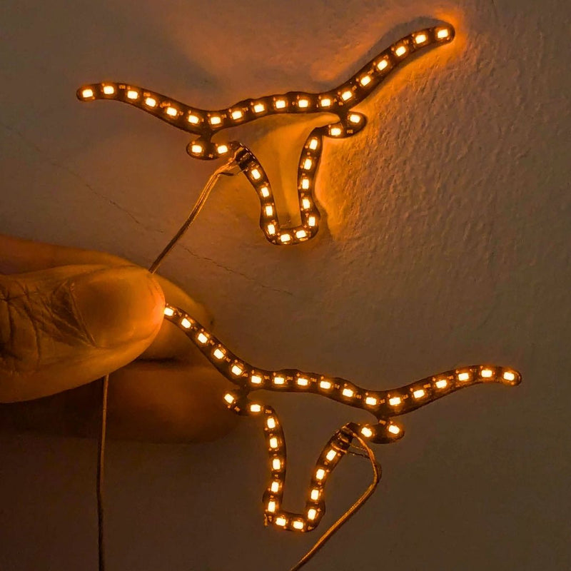 Neon Cowboys Longhorns LED face stickers glowing warm orange in a longhorn shape on skin, light up led face jewelry and rave face gems for game day, tailgates, concerts, raves and festival makeup looks, Neon Cowboys