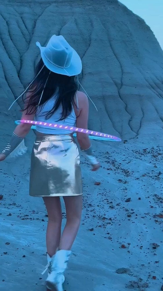 LED hula-hoop dancer in a Neon Cowboys white LED light-up cowboy hat in the desert at dusk