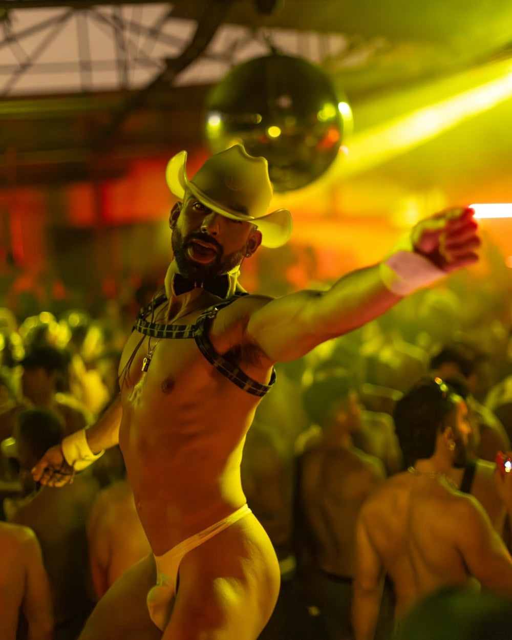 Male go-go dancer in a white Neon Cowboys LED light-up cowboy hat under a disco ball