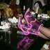 Legs in fishnets and purple glowing LED light up boots resting on a table with champagne glasses, these Out Past Midnight light up heels and light up cowgirl boots are made for raves, nightclub nights and bachelorette parties, Neon Cowboys