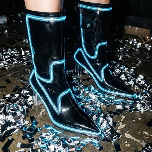 A model in black boots glowing blue standing on silver confetti at a night party, these Out Past Midnight light up cowgirl boots and light up heels are made for raves, New Year's Eve parties and nightclub nights, Neon Cowboys