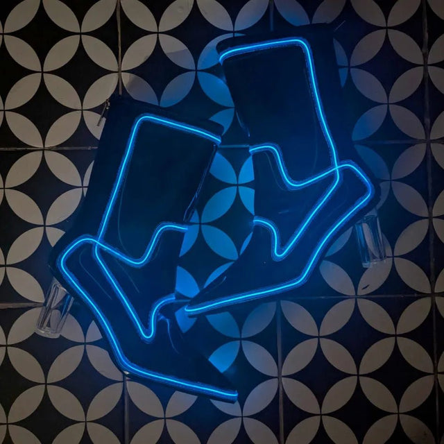 Black light up boots glowing blue arranged on a patterned tile floor, these Out Past Midnight light up cowgirl boots and light up heels are made for raves, festivals and nightclub nights, Neon Cowboys