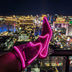 A raised leg showing a pink glowing LED light up boot against the Las Vegas skyline at night, these Out Past Midnight light up cowboy boots and light up heels are made for Vegas nights, raves and bachelorette parties, Neon Cowboys
