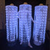 Neon Cowboys Remote Controlled LED Fringe Cowboy Hats glowing white-blue with full floor-length fiber-optic fringe cascading to the floor on three performers — color-changing light-up performance costume for touring dancers, drag shows, go-go and event entertainment