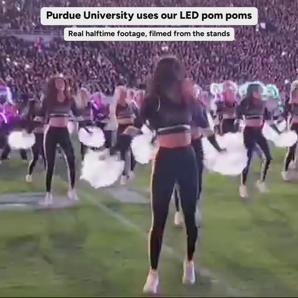 Real fan video of Purdue University's dancers using Neon Cowboys LED pom poms during the halftime show at a night football game; the poms switch from white to green, blue and pink mid-routine