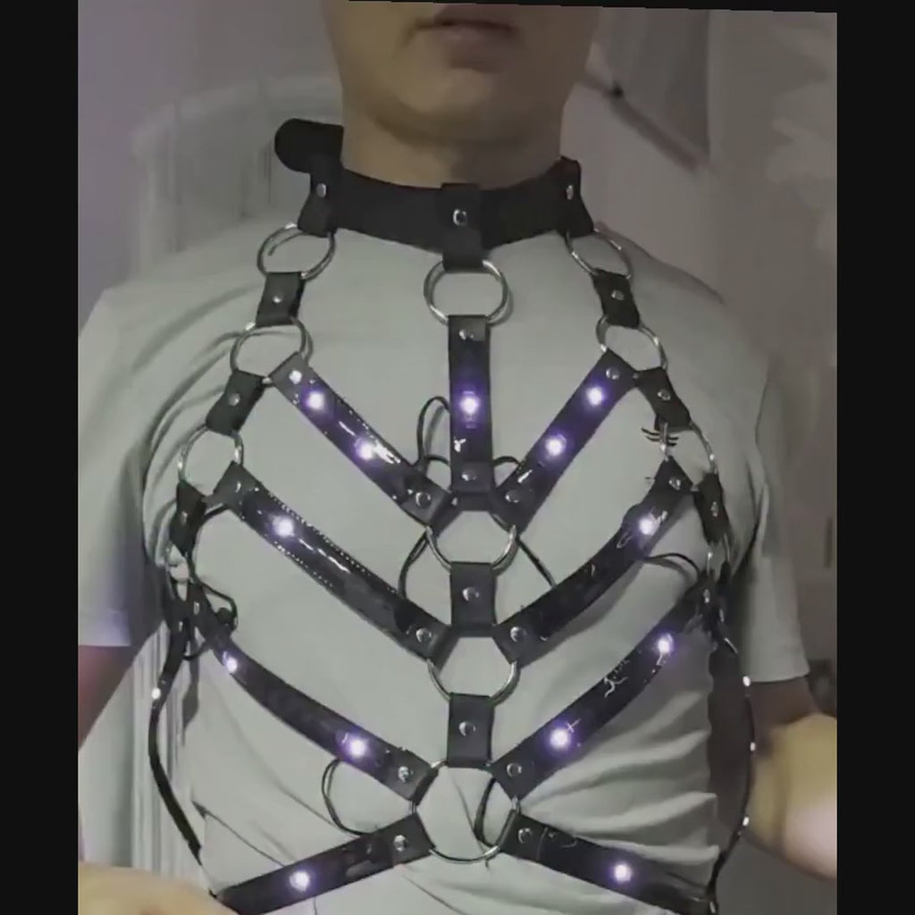 Man wearing the LED Rib Cage Harness over a grey T-shirt, using the remote to switch the chevron rib LEDs between rainbow, blue, orange and green — unisex fit