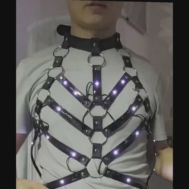 Man wearing the LED Rib Cage Harness over a grey T-shirt, using the remote to switch the chevron rib LEDs between rainbow, blue, orange and green — unisex fit