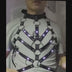 Man wearing the LED Rib Cage Harness over a grey T-shirt, using the remote to switch the chevron rib LEDs between rainbow, blue, orange and green — unisex fit