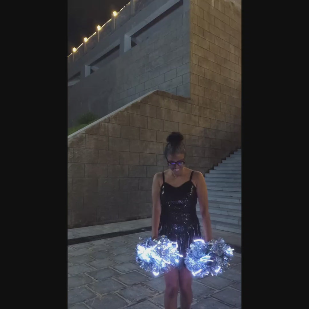 Light up LED pom poms glowing and changing colors — cordless color-changing LED cheer pom poms shown in motion, made-to-order glow pom poms for cheerleading, dance teams and stage performers.