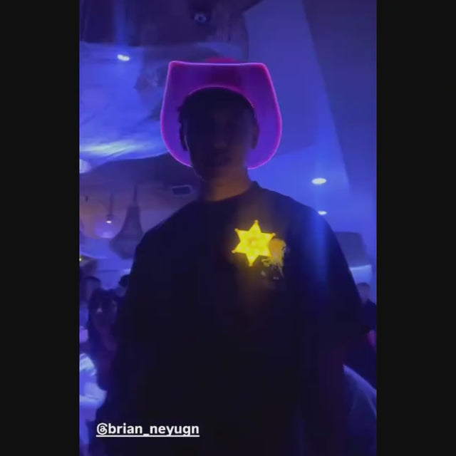 Person wearing yellow LED sheriff badge in dark environment - Light-up police accessory creating dramatic effect for nighttime events, costume competitions, themed parties, and western photoshoots