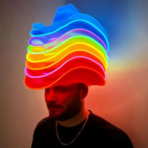 Man wearing stack of glowing blue and rainbow LED light up cowboy hat creating stunning silhouette for nighttime country concerts and western themed parties featured in New york times