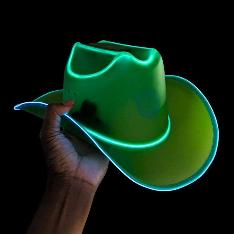 A hand holding a green recycled sustainable plastic LED cowboy hat with glowing blue trim in the dark, a color transition light up cowboy hat and glow in the dark western headwear made from recovered production material for festivals, rodeos, raves, nightclubs and country music events, Neon Cowboys