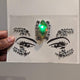 Hand holding rhinestone LED face gem sticker sheet - Adhesive-backed illuminated facial jewelry for easy application before raves, costume parties, Pride celebrations, and beauty photoshoots