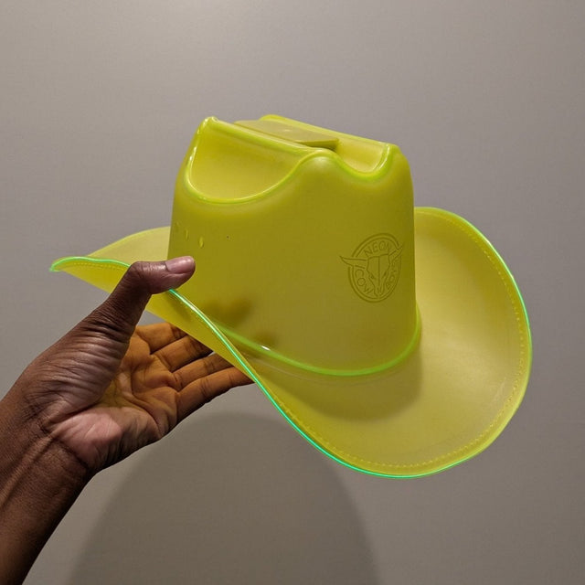Hand holding yellow cowboy hat in natural light - Limited Edition NC® Hat showing daytime color before LED illumination