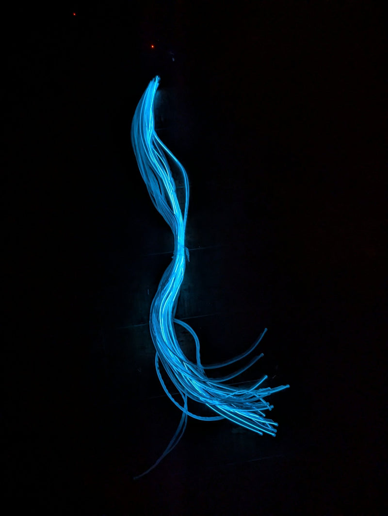 Bundle of Neon Cowboys sewable cool white EL wire strands glowing bright blue against a black background, a 34-inch individual strand of flexible blue-white electroluminescent wire for costume illumination, DIY led costumes, festival outfits and rave cosplay, Neon Cowboys