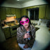 Woman in a fur coat wearing pink LED space sunglasses in a retro kitchen, futuristic cyberpunk LED glasses and space glasses with tron-style geometric frames, party sunglasses and festival sunglasses perfect for raves, EDM concerts, Y2K parties and cosplay, Neon Cowboys