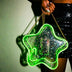 Woman in a black sequin skirt holding a green glowing LED light up star crossbody bag with a gold chain, star purse and clear bag concert accessory for music festivals, EDM raves, and stadium concerts with a clear bag policy, Neon Cowboys
