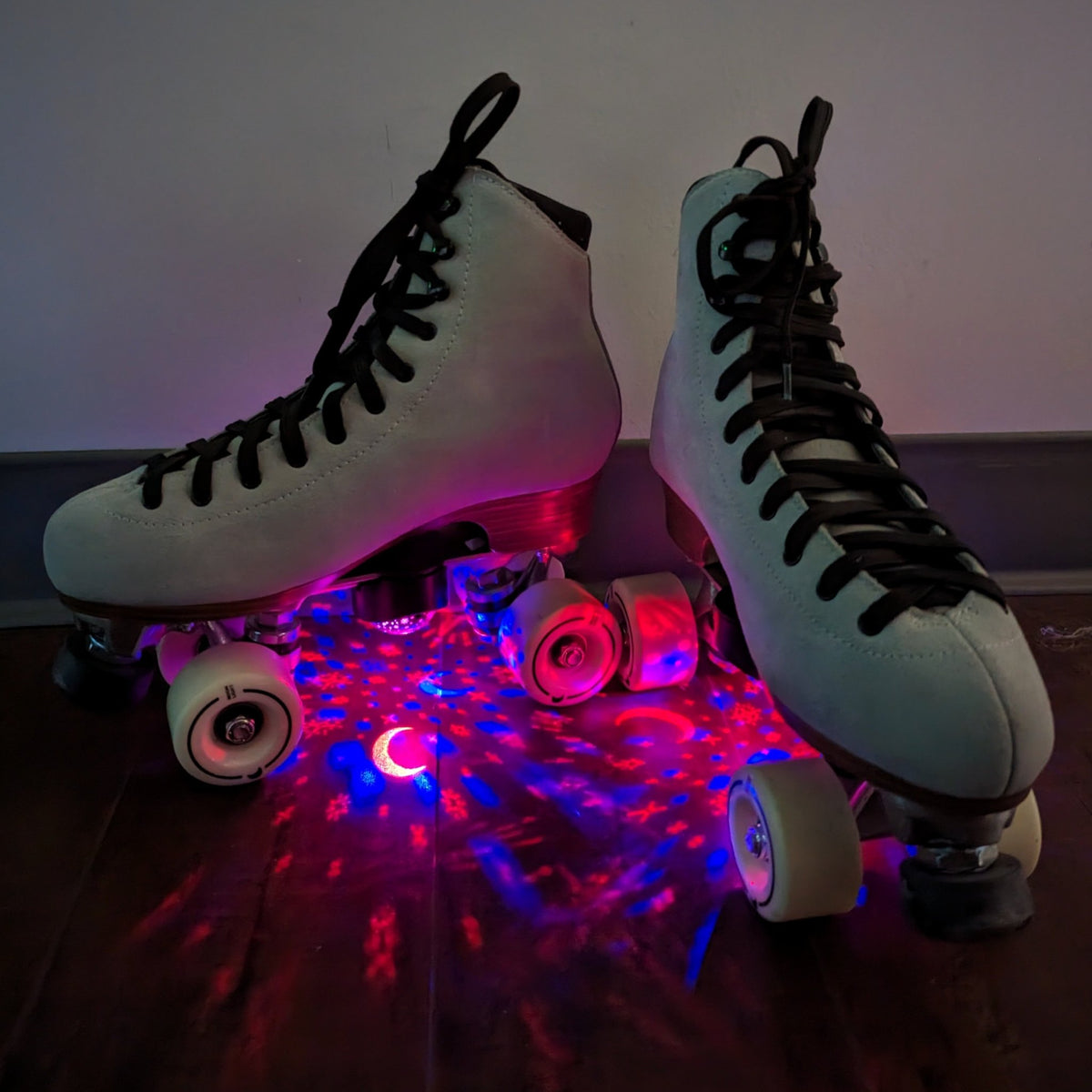 Close-up of roller skates with illuminated star projectors showing pink and red light pattern effects for enhanced skating visibility and aesthetic appeal
