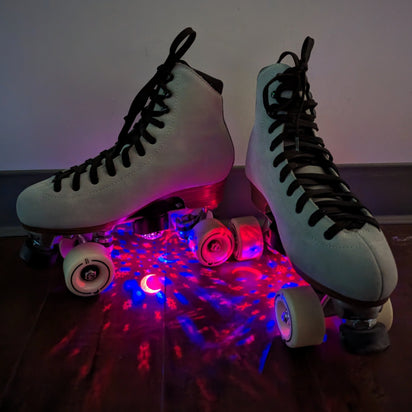 Close-up of roller skates with illuminated star projectors showing pink and red light pattern effects for enhanced skating visibility and aesthetic appeal