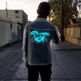Man wearing light-up horse jacket from behind showing glowing blue animated running horse design perfect for night motorcycle riding and space cowboy festival outfits