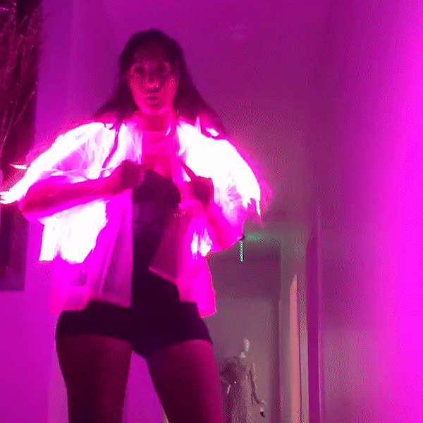 Close-up of glowing pink LED fringe jacket in dark venue demonstrating vibrant illumination for stage performances clubs and nighttime events