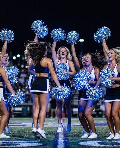 Cheer squad glowing with LED light-up pom poms on a night field &mdash; Neon Cowboys cheer & dance gear
